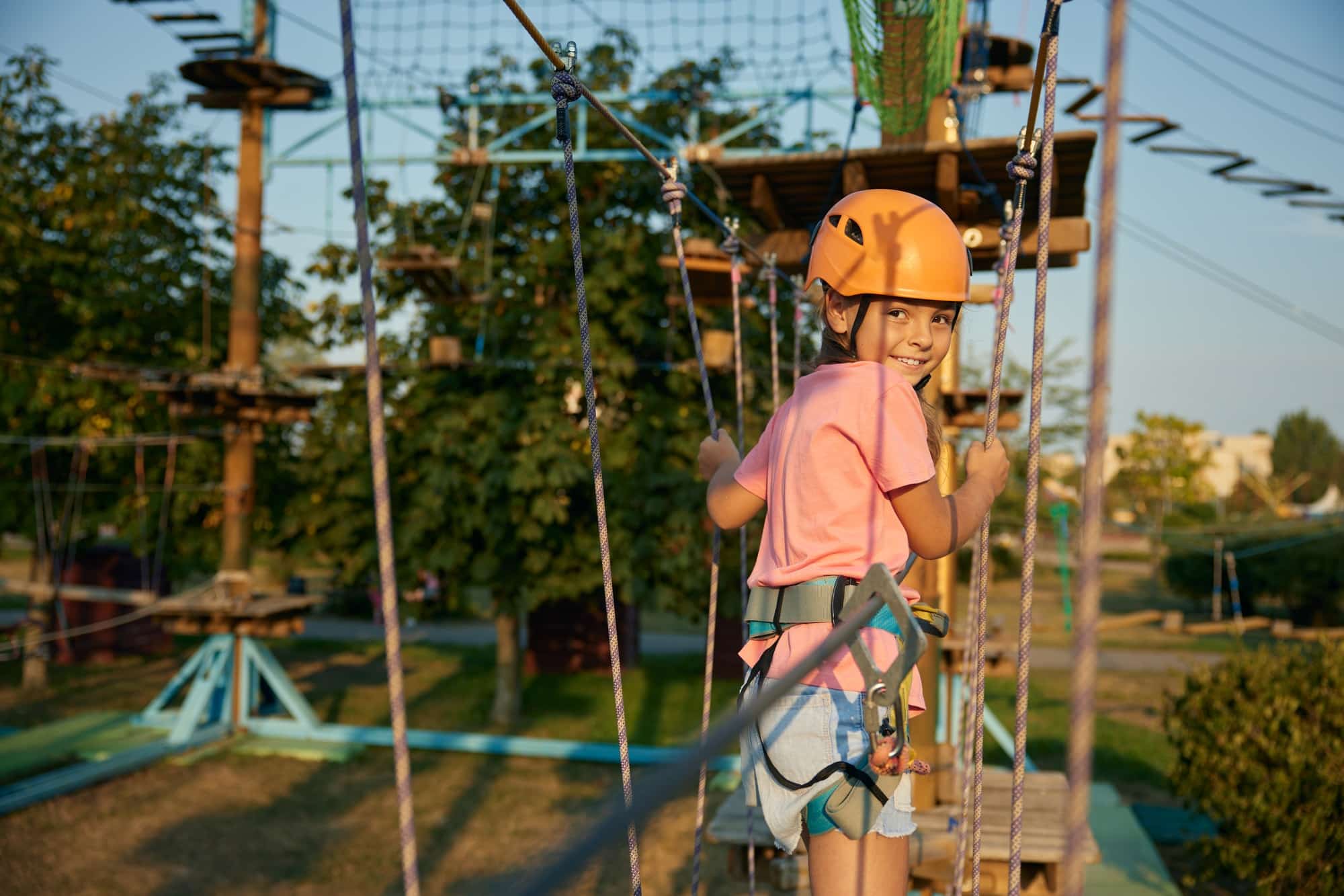 Smiling little girl child feeling happiness due to successful climb in rope park
